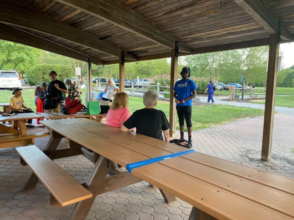 towamencin-home-rule-charter-5 A man talks in front of a group of people seated at picnic tables in an outdoors area.