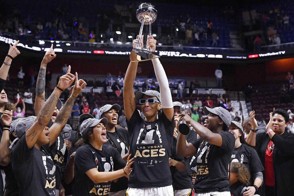 WNBA Finals Basketball A basketball player holds up a trophy as her teammates surround her to celebrate.