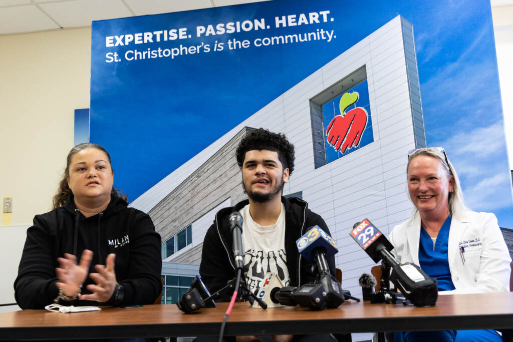 10 18 2022 k paynter ivan 17 year-old recovery from gunshot to head Mom Natali Rosario (left), 17 year-old Ivan (center) and pediatric neurosurgeon Dr. Tina Loven (right) spoke to the media about Ivan’s recovery a year after he was shot in the head near his high school, October 18, 2022. (Kimberly Paynter/WHYY)