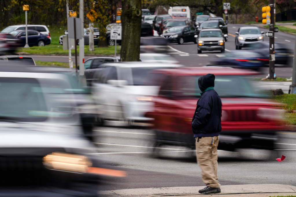 Roosevelt Boulevard (AP) A pedestrian waits to cross Roosevelt Boulevard, in Philadelphia, Tuesday, April 19, 2022. Roosevelt Boulevard is an almost 14-mile maze of chaotic traffic patterns that passes through some of the city’s most diverse neighborhoods and Census tracts with the highest poverty rates. Driving can be dangerous with cars traversing between inner and outer lanes, but biking or walking on the boulevard can be even worse with some pedestrian crossings longer than a football field and taking four light cycles to cross. (AP Photo/Matt Rourke)