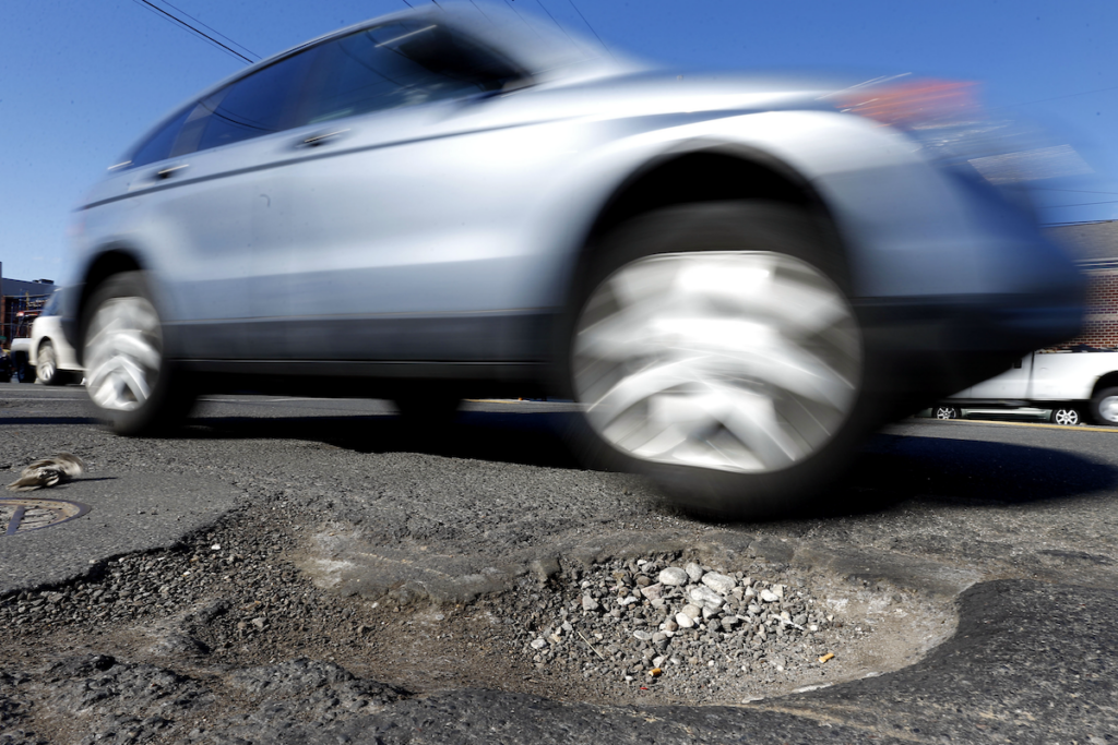 A vehicles drives past a pothole in Philadelphia on Monday, Feb. 24, 2014. Since Dec. 1, 2013, PennDOT workers have applied more than 2,000 tons of patching material in the five counties around the city, according to spokesman Gene Blaum. (AP Photo/Matt Rourke)