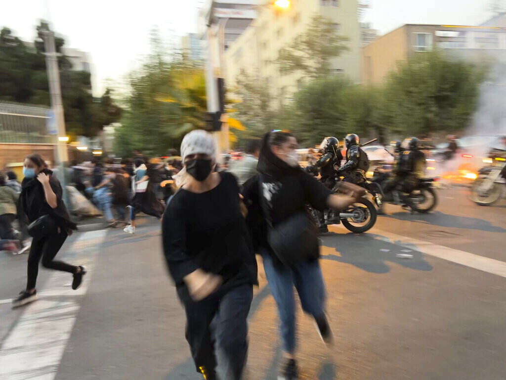 Iran Protest Women run away from anti-riot police during a protest of the death of a young woman who had been detained for violating the country's conservative dress code, in downtown Tehran, Iran. (AP Photo)