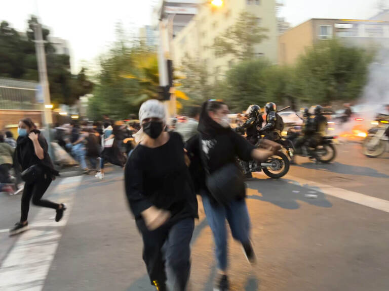 Women run away from anti-riot police during a protest of the death of a young woman who had been detained for violating the country's conservative dress code, in downtown Tehran, Iran. (AP Photo)