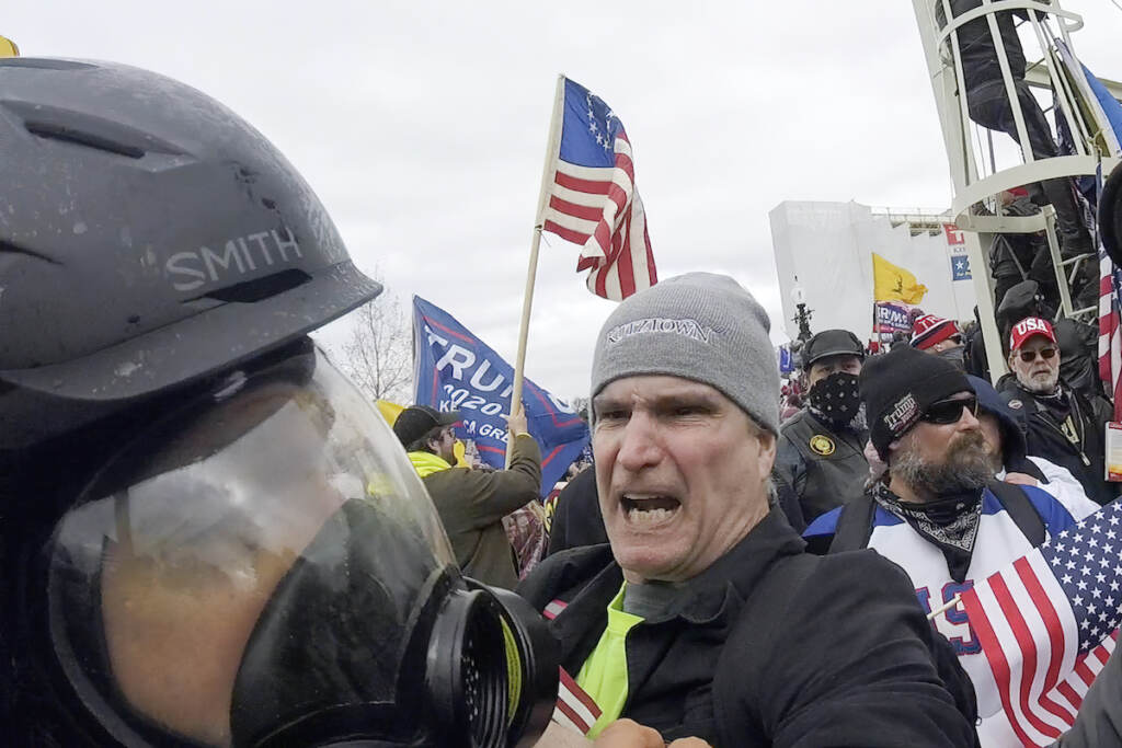 File: In this image from video, Alan William Byerly (center) attacks an Associated Press photographer during a riot at the U.S. Capitol in Washington, Jan. 6, 2021. On Sunday, Oct. 9, 2022, federal prosecutors recommended a prison sentence of nearly four years for Byerly, of Pennsylvania, who pleaded guilty to assaulting the AP photographer and using a stun gun against police officers during a mob's attack on the U.S. Capitol. (AP Photo/Julio Cortez, File)