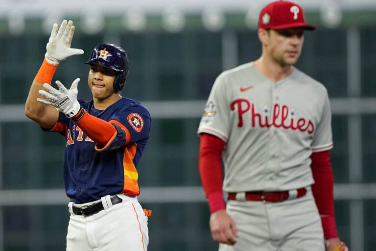 An Astros player celebrates as a blurry Phillies player looks dejected in the foreground.