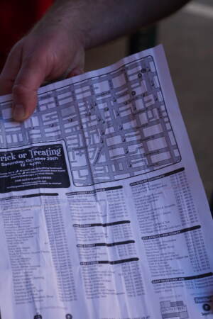A dad holds the map of participating trick-or-treat businesses. (Sam Searles/WHYY)