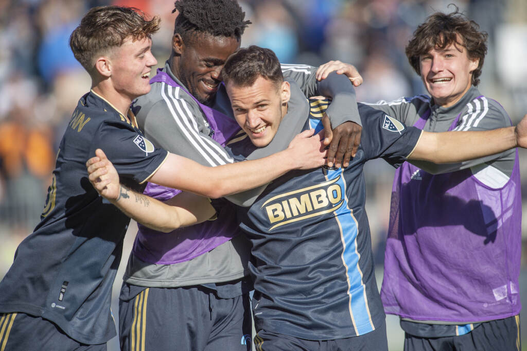 Union-Toronto-4 – Copy Soccer players surround and hug one soccer player who is smiling.