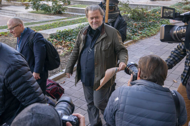 Steve Bannon is surrounded by reporters outside of a courtroom.