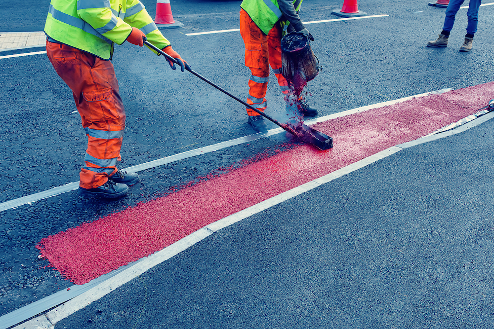 Road Workers Applying Hot Red Road Marking Paint On New Build Road Road workers applying hot red road marking paint on new build road