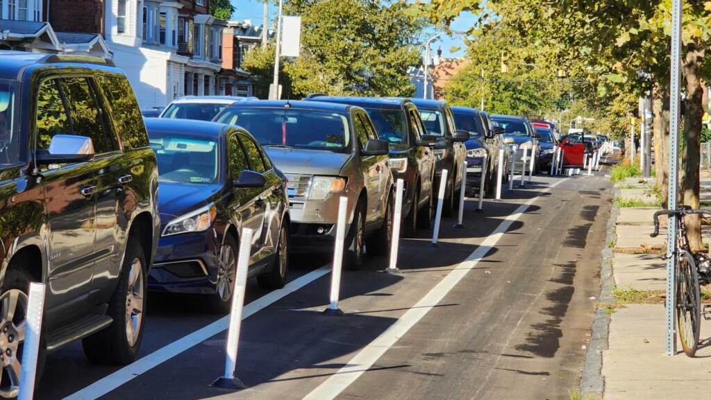bike-lanes-2 A bike lane is separated by white poles from parked cars.