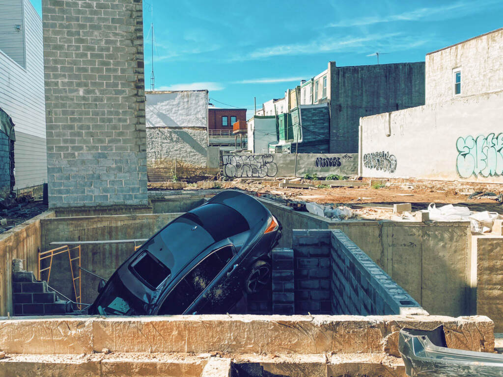 carcrash-frankford-construction-foundation-02 A car sticks out of a hole in a construction site.