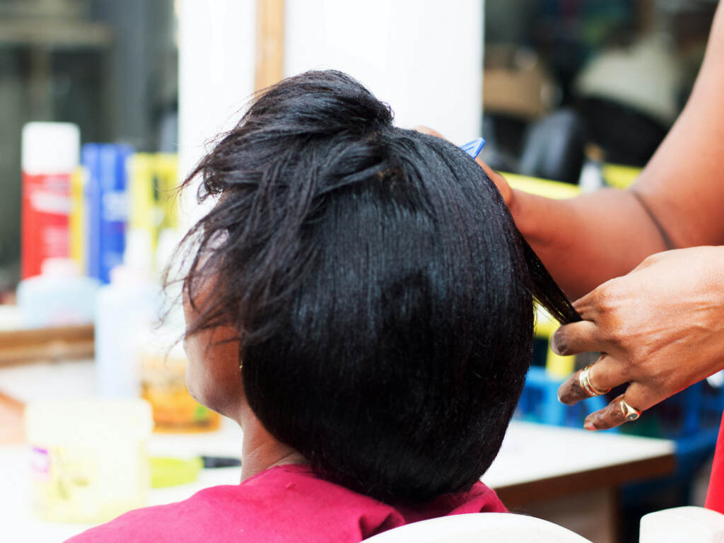 A woman has her hair chemically straightened at a salon