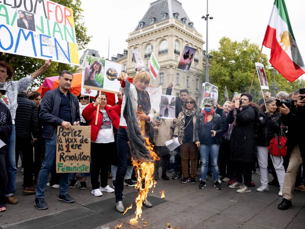 A woman burns headscarves during a demonstration in support of Kurdish Iranian woman Mahsa Amini during a protest on Sunday on Place de la Republique in Paris, following Amini’s death in Iran. A woman burns headscarves during a demonstration in support of Kurdish Iranian woman Mahsa Amini during a protest on Sunday on Place de la Republique in Paris, following Amini's death in Iran.
Stefano Rellandini/AFP via Getty Images