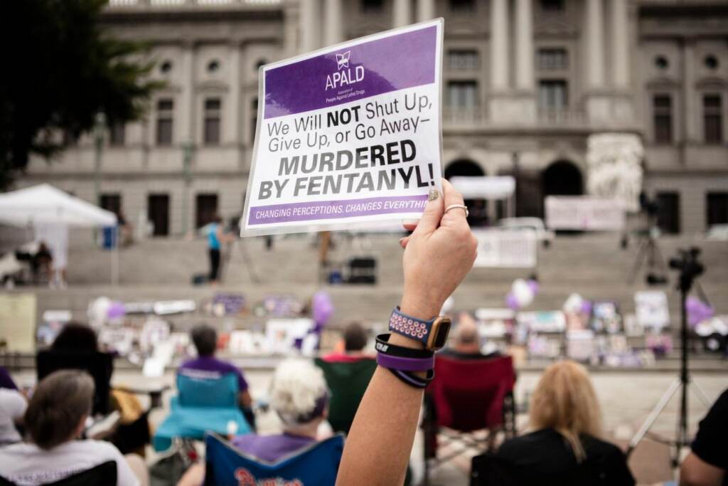 governor-race-2022-healthcare-opioid-epidemic A person holds up a sign in a crowd.