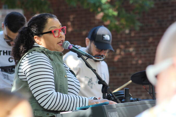A person plays the keyboard and sings into a microphone.