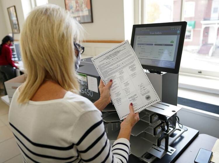 A person holds a mail ballot in their hand.