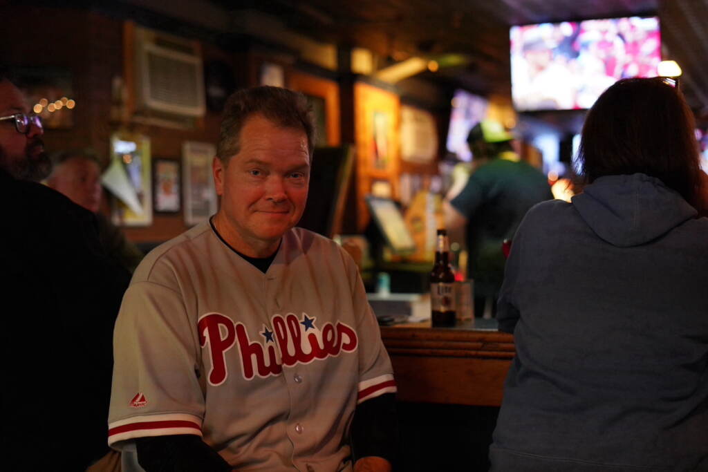 pa-election-2022-suburban-voters-2 A man wearing a Phillies jersey sits at a bar.