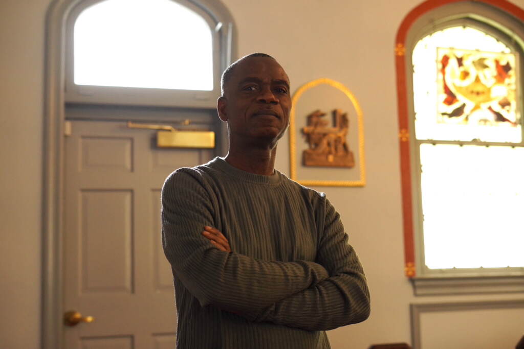 A man stands with his arms folded in a building.