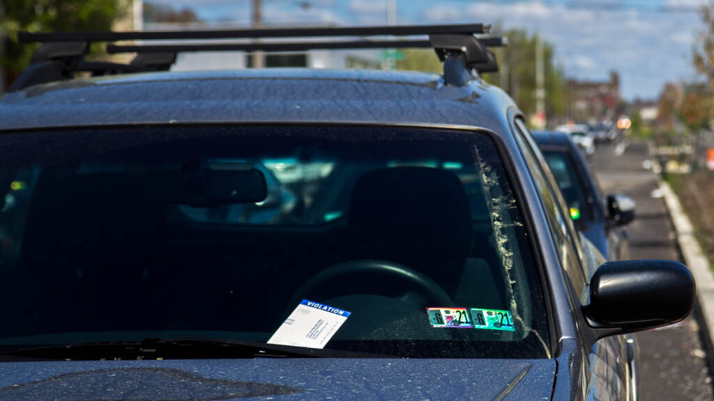 A parking ticket sits on the windowshield of a car.