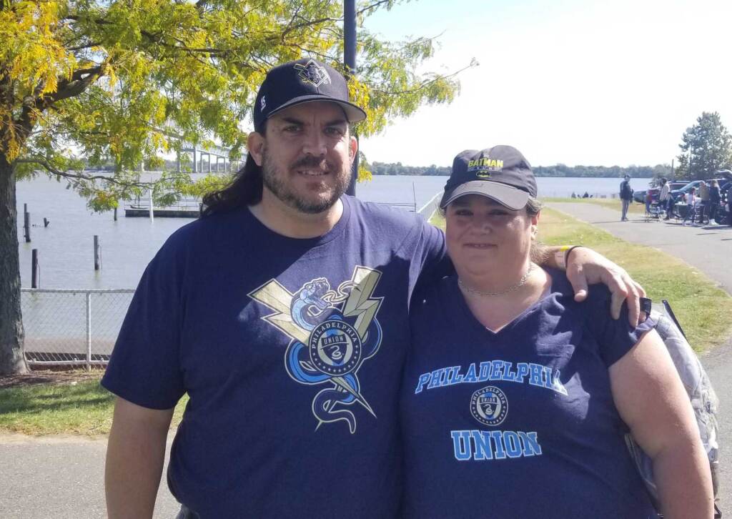 A couple pose for a photo outdoors.