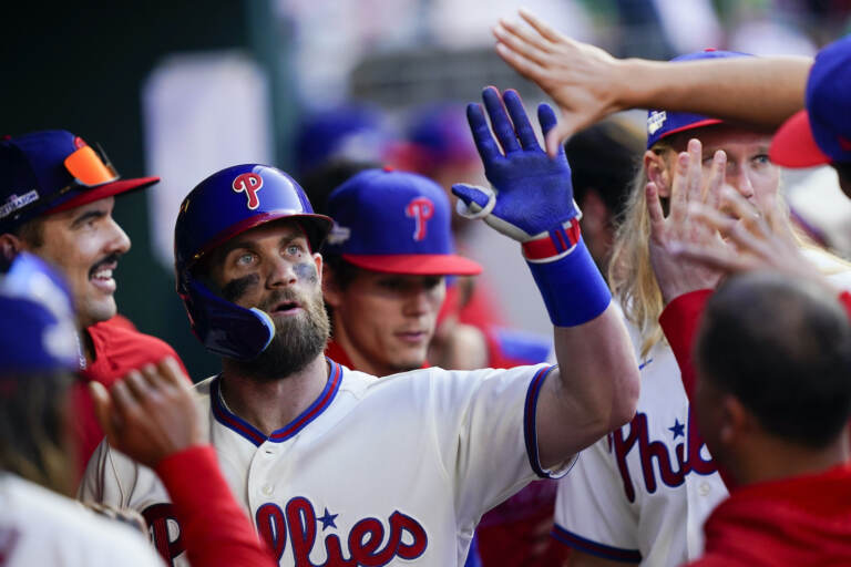 Bryce Harper, center, celebrates with his team in the Phillies dugout