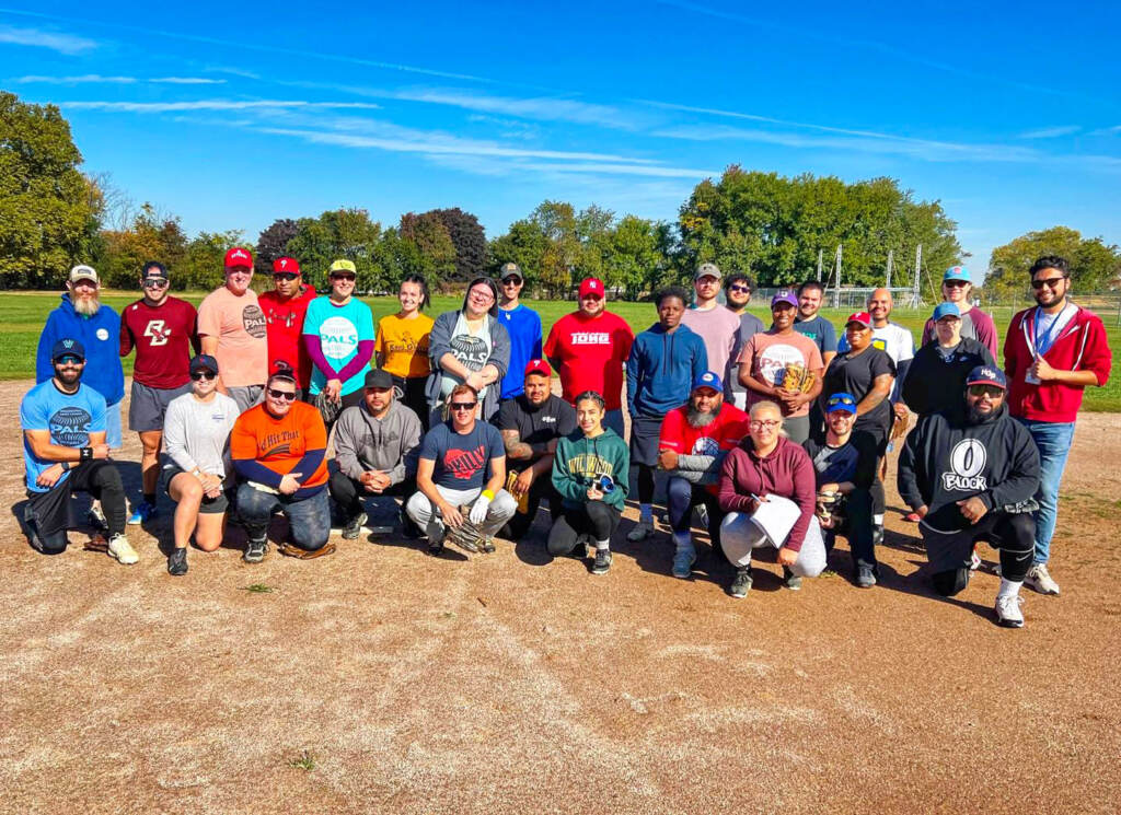 A group of softball players pose on a softball field