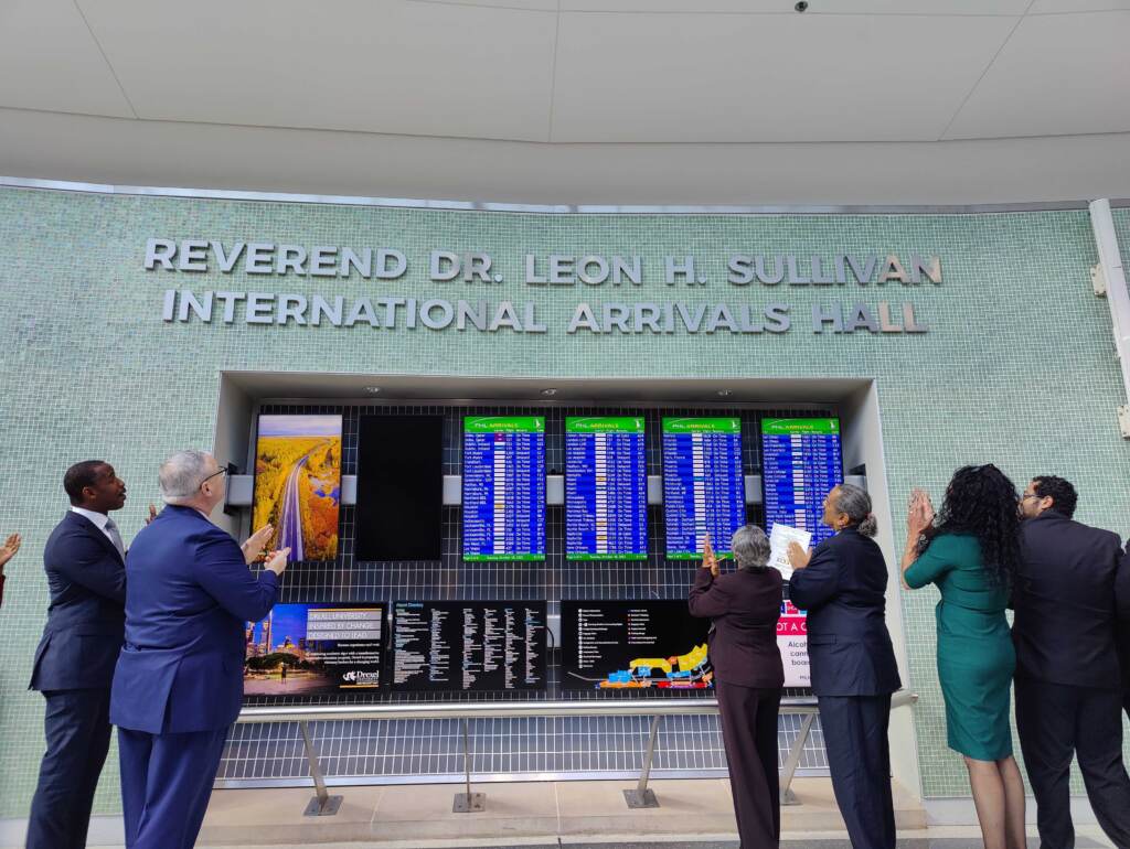 phl-airport-p-crimmins-2022-10-18-1 Mayor Jim Kenney (in blue) and Mable Ellis Welborn (in maroon), board chair of the Leon H. Sullivan Charitable Trust, unveil the new name of the international arrivals hall at the Philadelphia airport. (Peter Crimmins/WHYY)