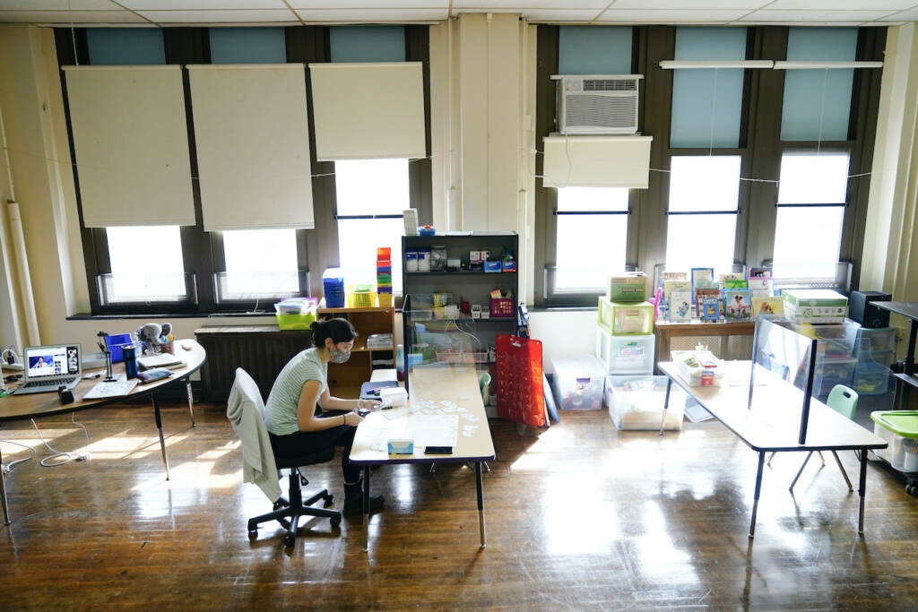 Laura Bonanni A teacher sits at a desk in an empty classroom.