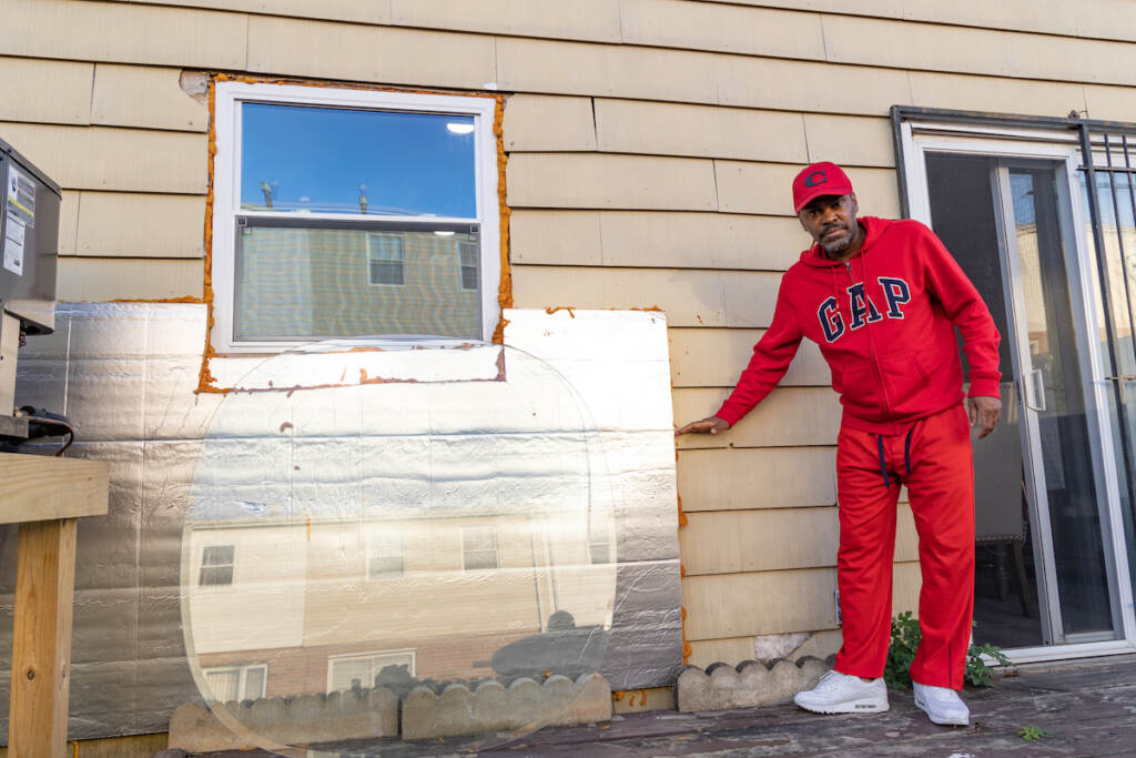 Lemuel Bannister estimates the height of the flooding caused by Isais in 2020. Holes along the bottom of the siding are covered up with an insulation board to keep his pipes from freezing in the winter. (Kimberly Paynter/WHYY)