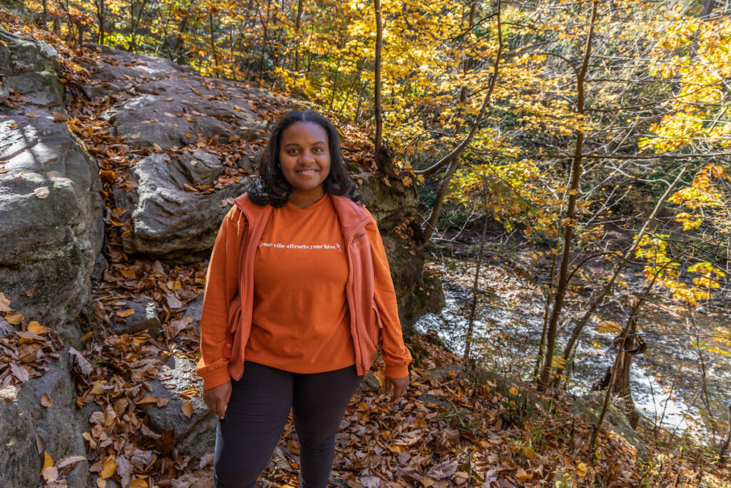 A woman poses in the woods.