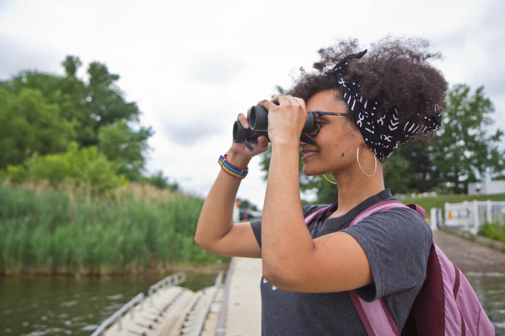 A woman at a park holds up binoculars.