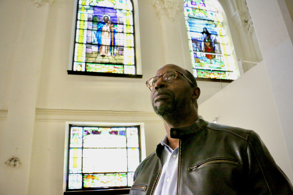 2022 11 03-e lee-milchael major sr-philadelphia zion baptist church annex-sanctuary A man looks upward. Behind him are stained glass windows.