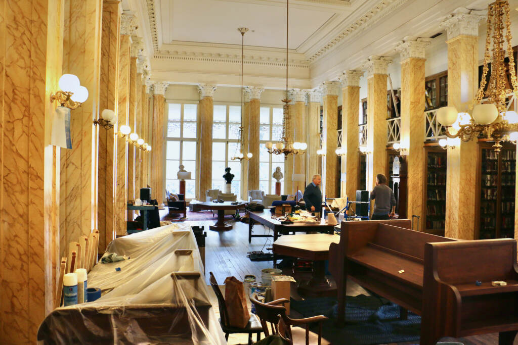 2022 11 04-e lee-philadelphia athenaeum-removations reading room Workers make renovations in an ornate room with plastic draped over some of the desks.