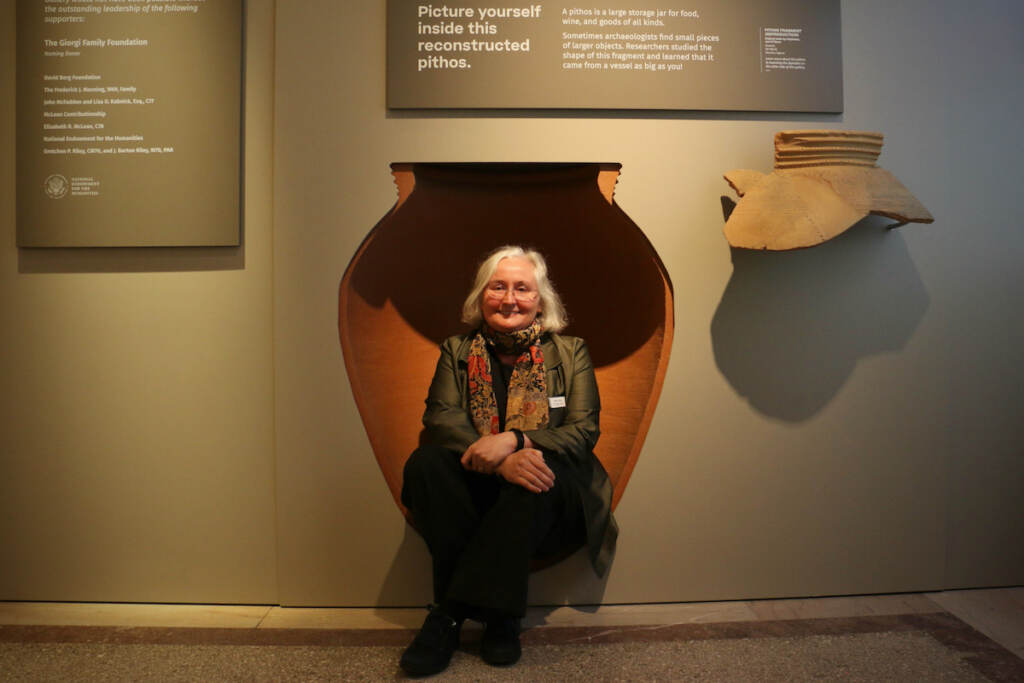 A person sits inside of a structure in a museum exhibition.