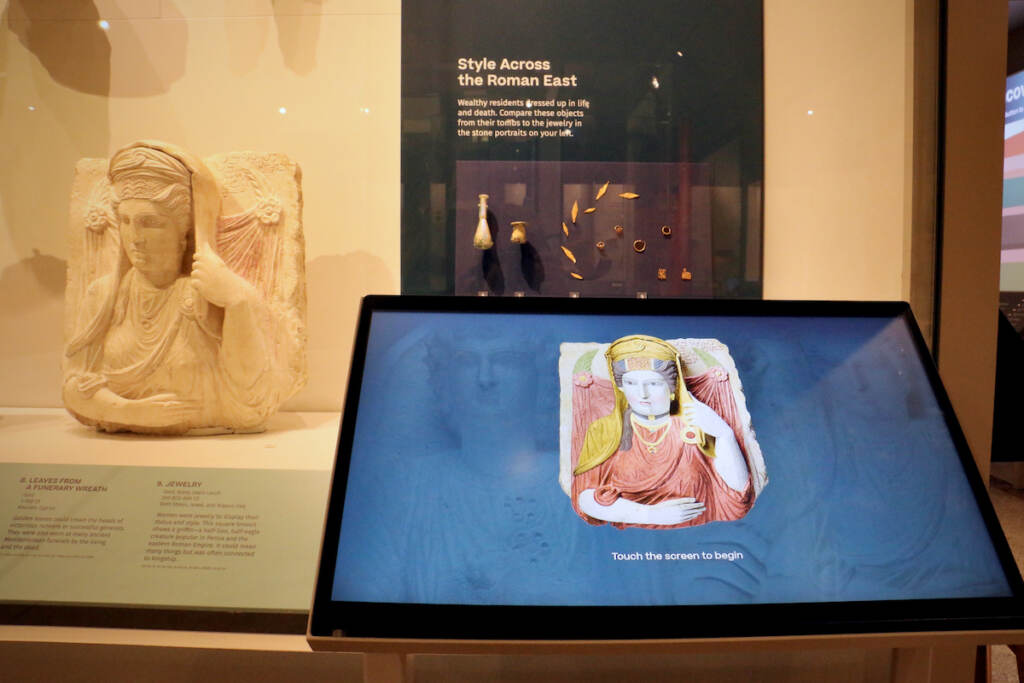 A funerary bust is visible in a museum exhibition.