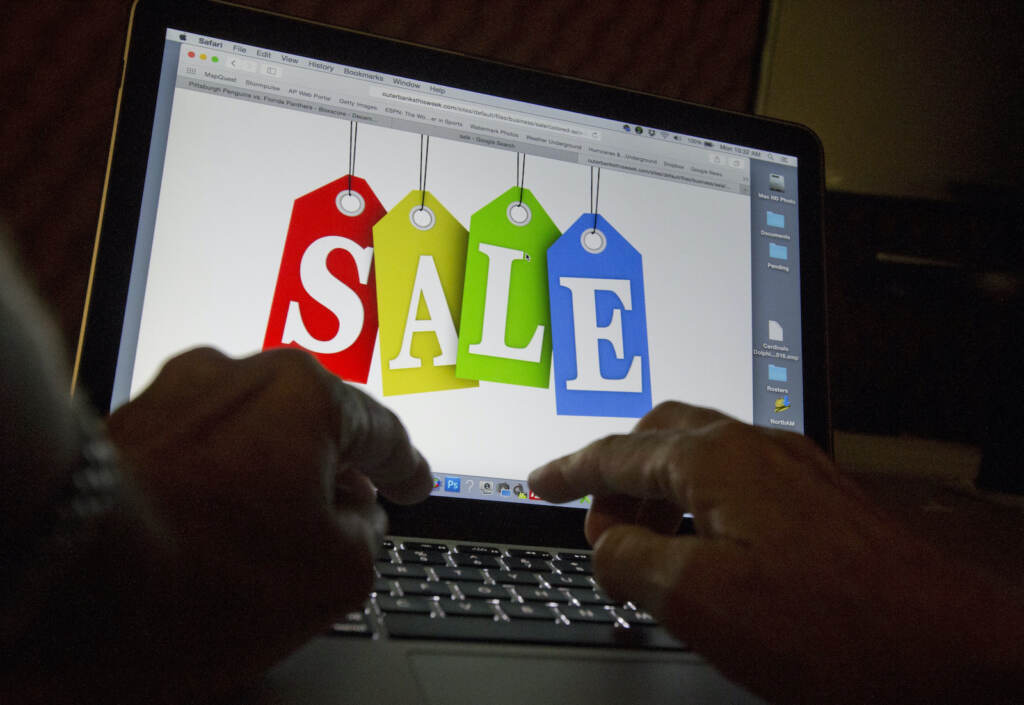 Cyber-Monday A person's hands are seen on a keyboard in front of a computer screen that has the word 'SALE' written on it