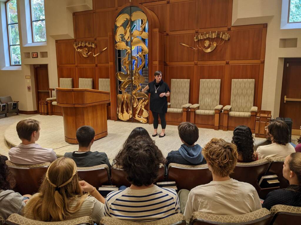 fischel1-43fe5d501f8d5608fca171a090962901168e012b-s1600-c85 A rabbi addresses a group of people in a synagogue.
