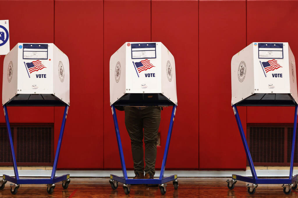 New Yorkers Head To Polls To Elect A New Mayor A person's legs are visible as they stand behind a voting booth.