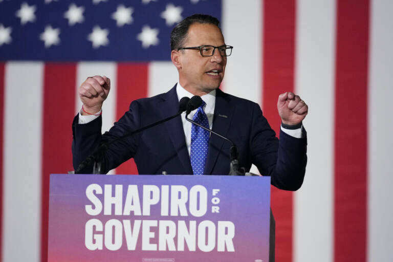 Josh Shapiro gestures in front of an American flag