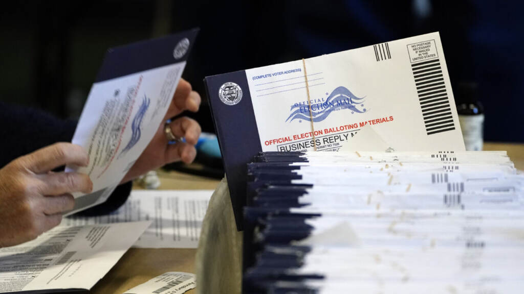 Election 2020 Pennsylvania Voting A person handles a mail ballot as a stack of mail ballots sit in front of them.