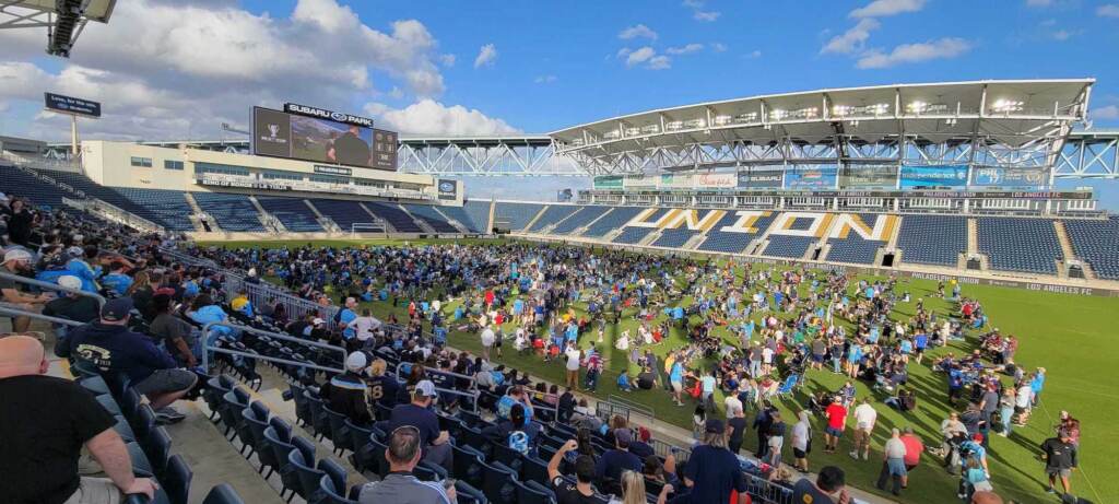 People gather in the stands and on a soccer field.