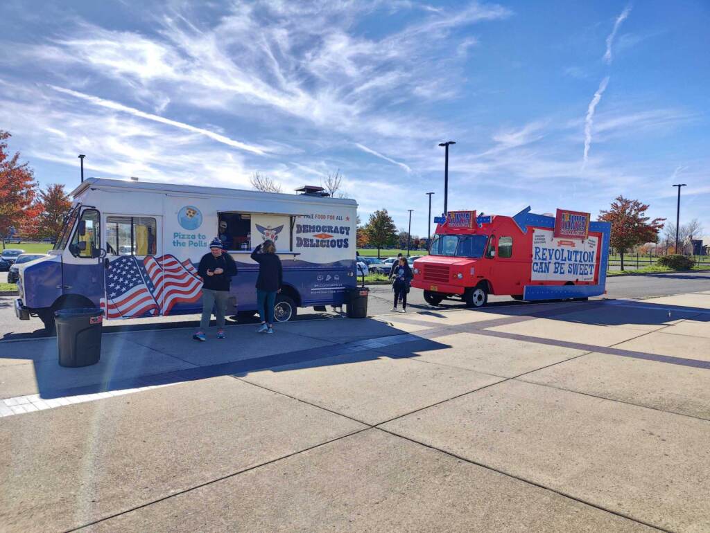A pizza truck is parked on a sidewalk.