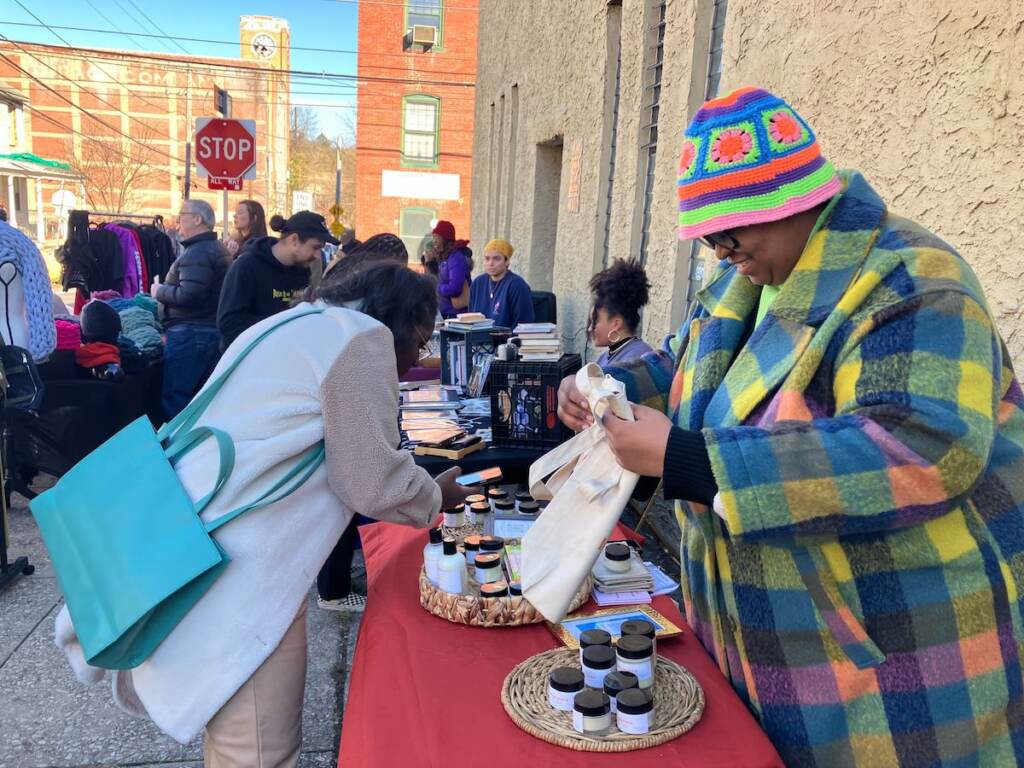 small-biz-sat-3 A vendor smiles as she prepares a purchase for a customer at her table.
