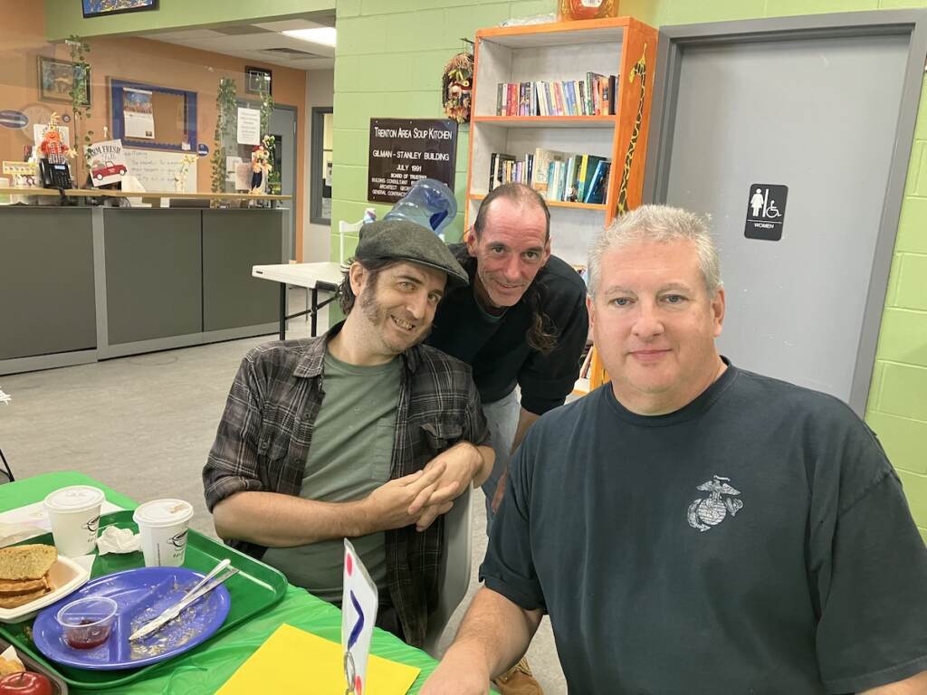 Three people pose for a photo seated at a table.