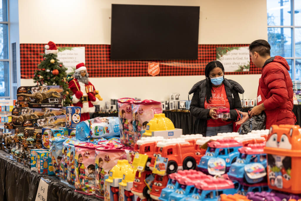 12 15 2022 k paynter salvation army toy shop 2022 People look at toys in a large room.