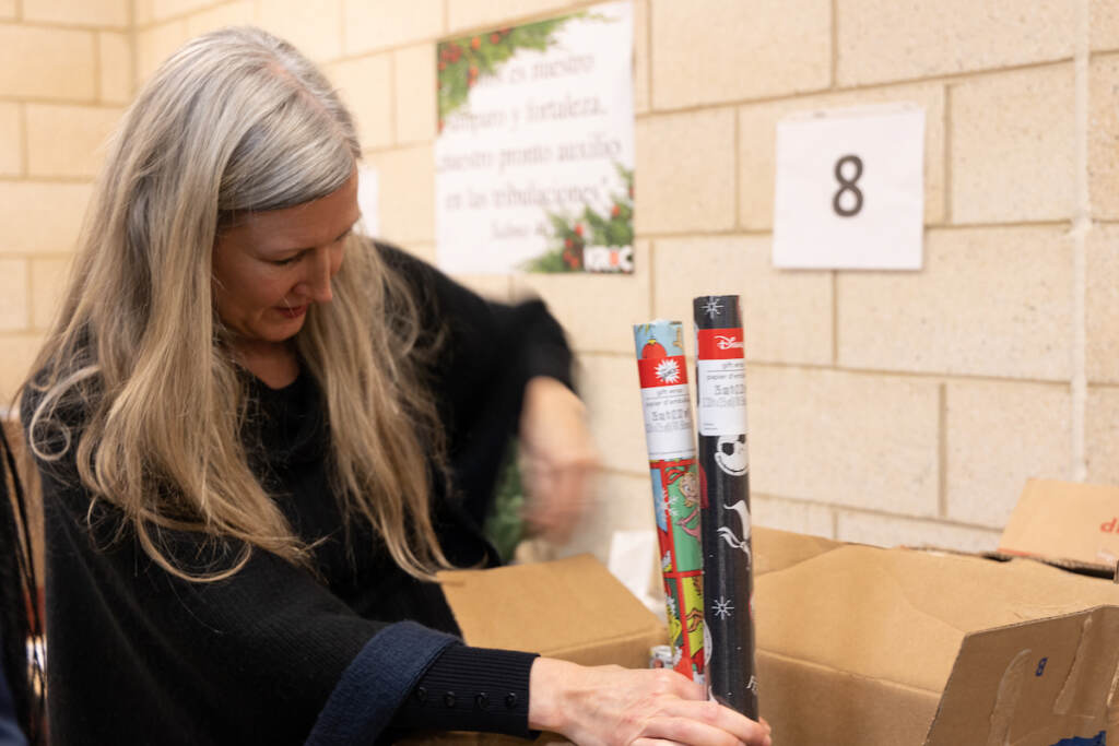 A woman holds rolls of wrapping paper.