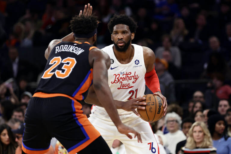 Philadelphia 76ers center Joel Embiid (21) looks to pass around New York Knicks center Mitchell Robinson during the first half of an NBA basketball game, Sunday, Dec. 25, 2022, in New York. (AP Photo/Adam Hunger)