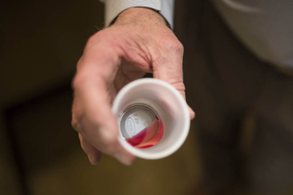 A person holds a cup with medicine in it.