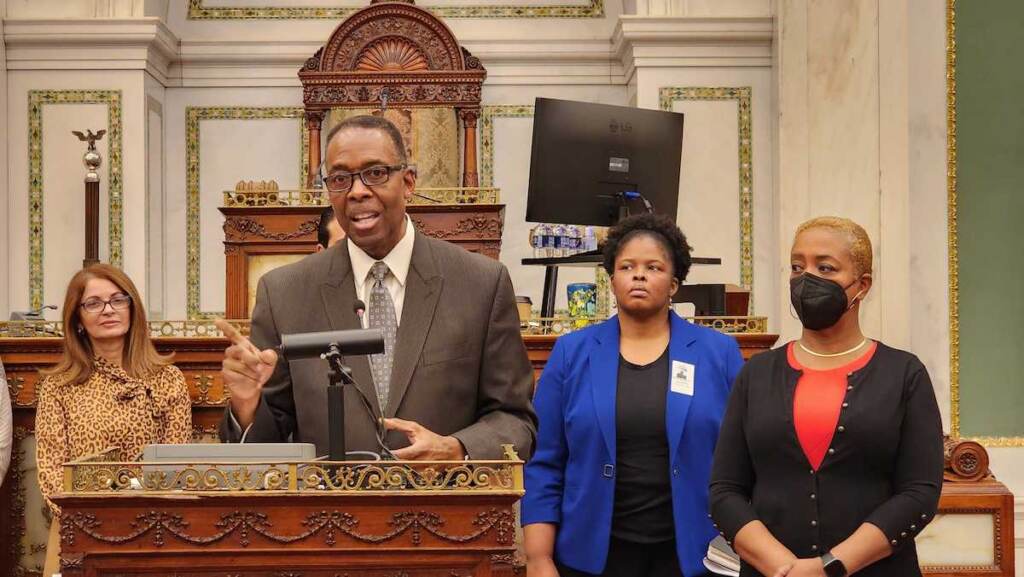 Council President Clarke speaks at a podium in City Hall.
