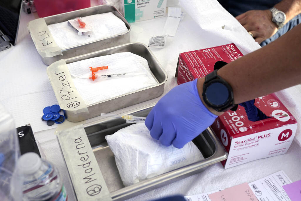 Modern and Pfizer COVID vaccines and flu vaccines sit in bins at a clinic